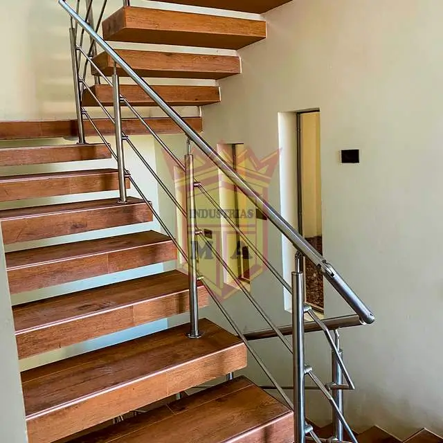 Barandal de acero inoxidable en una escalera interior con peldaños de madera
